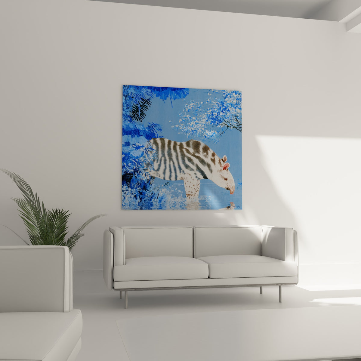 Silhouette de tapir bleu marine et blanc s'abreuvant, accrochée au-dessus d'un canapé dans un salon lumineux