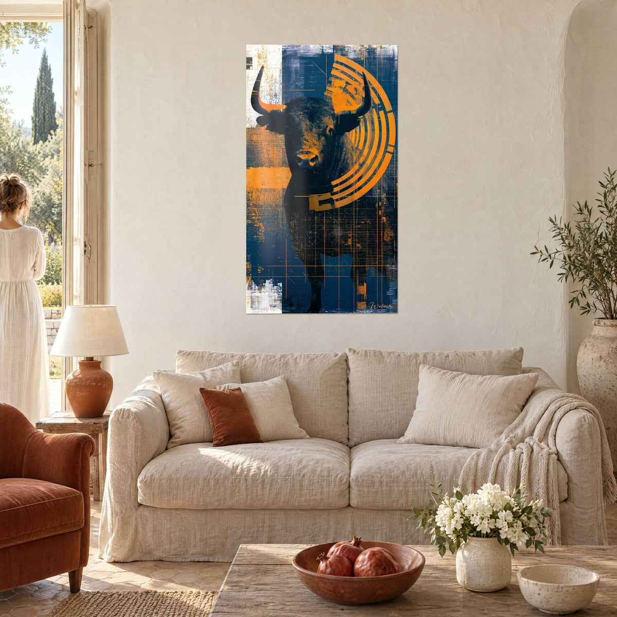 Wall art of a black bull with raised horns in front of orange half-circles on a midnight blue background, above a sofa in a bright living room