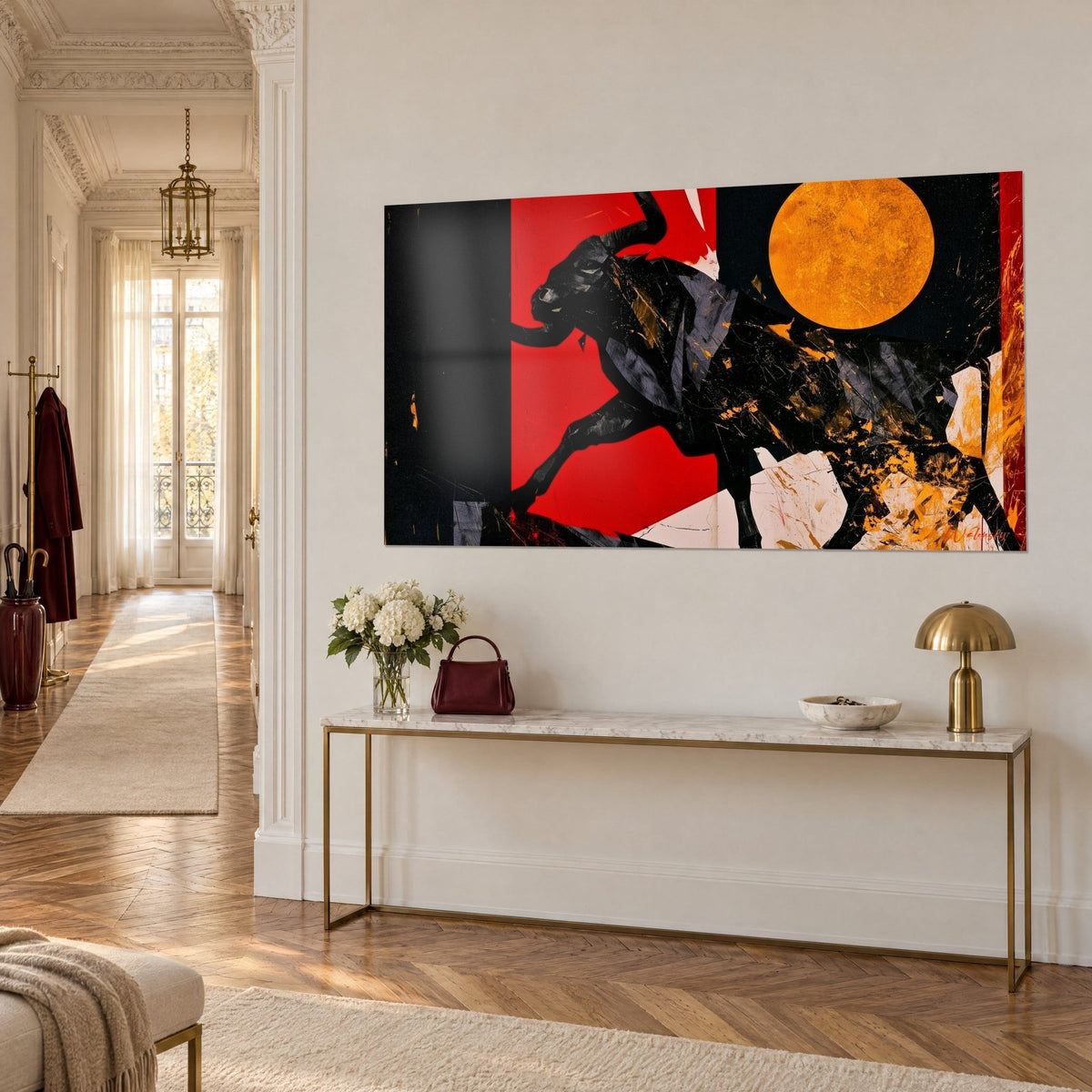 Wall art of a horned bull charging at full speed, ink silhouette on a scarlet panel with an orange moon, above a gilded console table