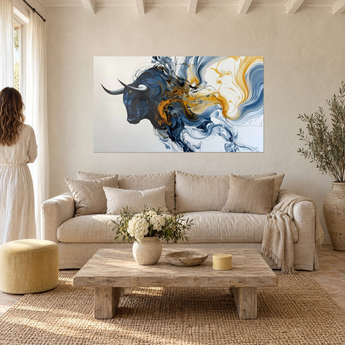 Quadro toro di profilo con corna nere, volute blu notte e dorate, donna di spalle, sopra un divano in un soggiorno luminoso