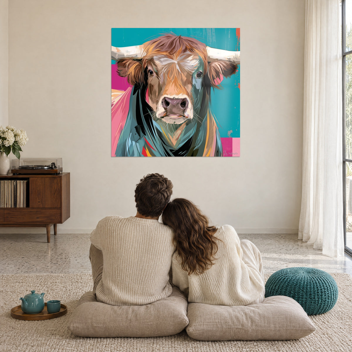 Gemälde Gegenüberstellung mit einem kupferfarbenen Stier mit cremefarbenen Hörnern, türkisfarbener und rosa Hintergrund, ein umschlungenes Paar von hinten auf Kissen im Wohnzimmer