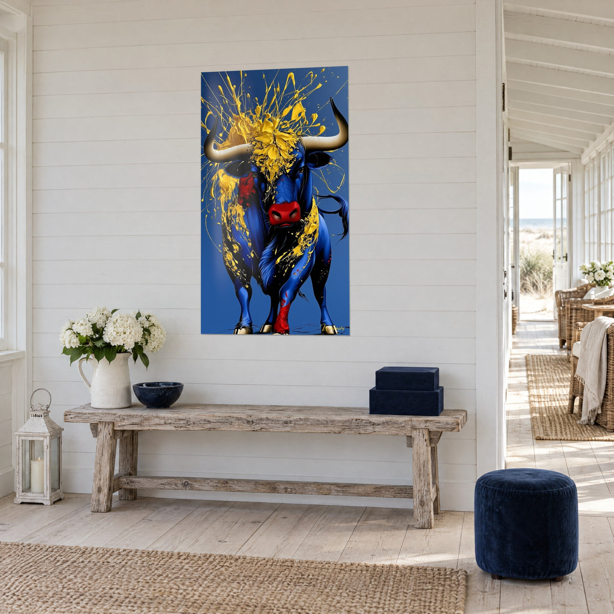 Schilderij van een massieve runder met ivoorkleurige hoorns, koningsblauwe vacht bespat met geel, opgehangen boven een consoletafel van drijfhout aan zee