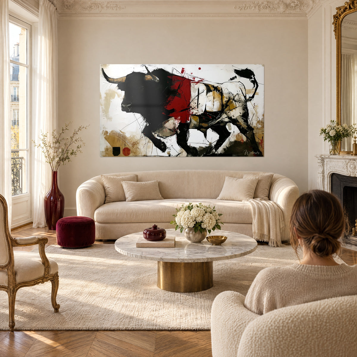 Cuadro de un toro negro de cuernos ocres, trazo carmesí en el flanco y fondo blanco salpicado, sobre un sofá en un salón luminoso