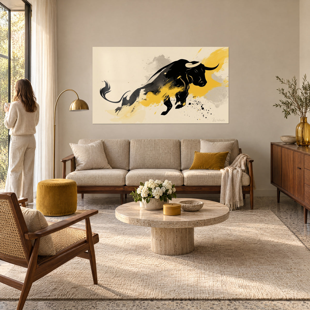 Gemälde Springender schwarzer Stier, senfgelbe und hellgraue Spritzer, Frau von hinten, über einem Sofa in einem hellen Wohnzimmer