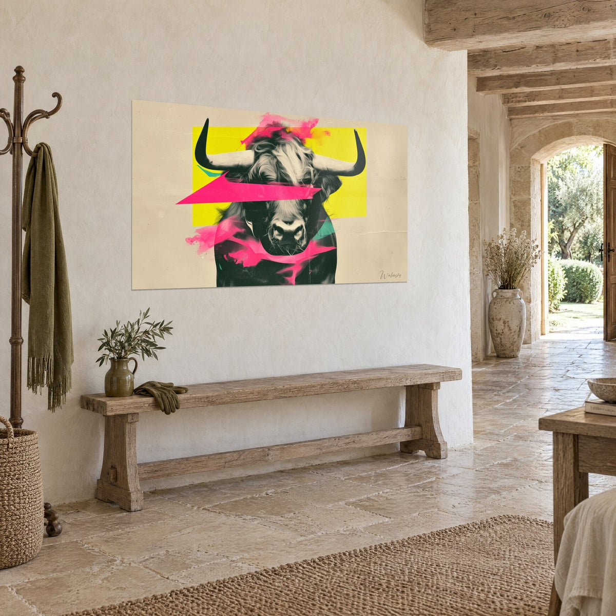 Quadro bovino dalle corna d'ebano, triangolo rosa acceso che copre lo sguardo, sfondo giallo, su un muro di pietra accanto a una panca