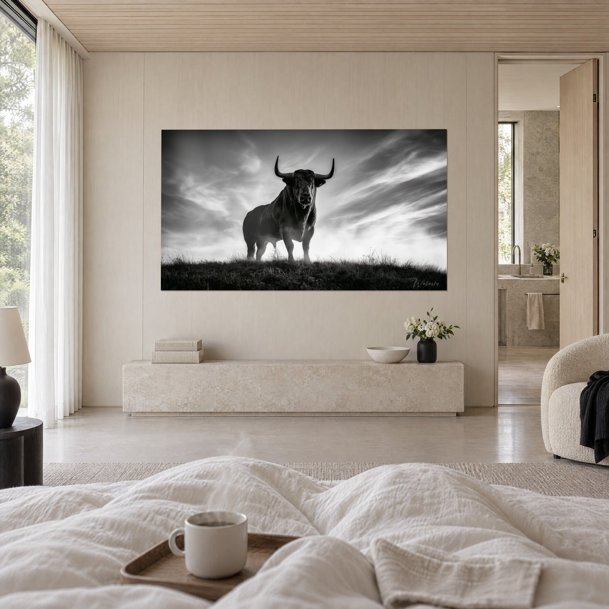 Cuadro de una criatura gigante con cuernos alzada en la colina, negro profundo y blanco brillante, nubes en volutas, sobre una cama en un dormitorio luminoso