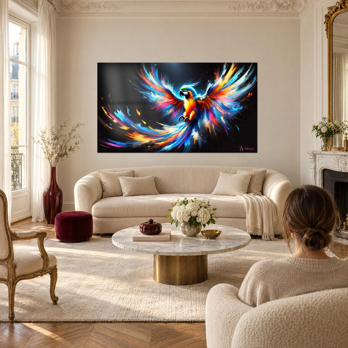 Tableau ara aux ailes déployées en bleu électrique et orange vif, fond noir, deux personnes de dos au-dessus d'un canapé dans un salon lumineux