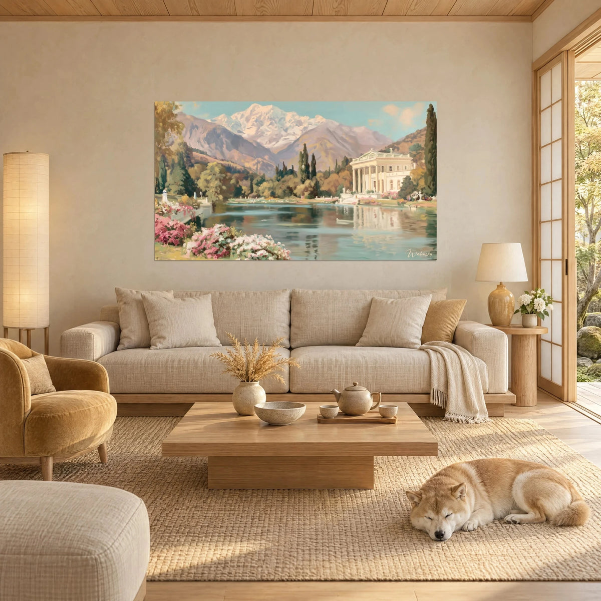 Quadro di una villa neoclassica con colonne bianche su un lago azzurro-verde, cime rosate e fiori rosa, sopra un divano in un soggiorno luminoso