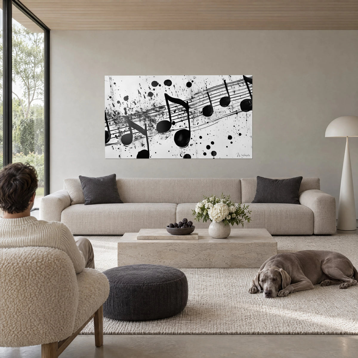 Wall art of a score splashed with black ink on a white background, round notes and staves, above a sofa in a bright living room