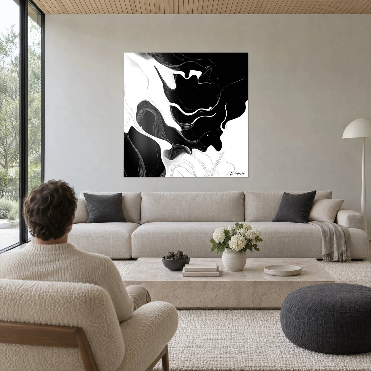 Tableau marbrure d'encre noire et blanche aux courbes fluides, homme de dos, au-dessus d'un canapé dans un salon lumineux
