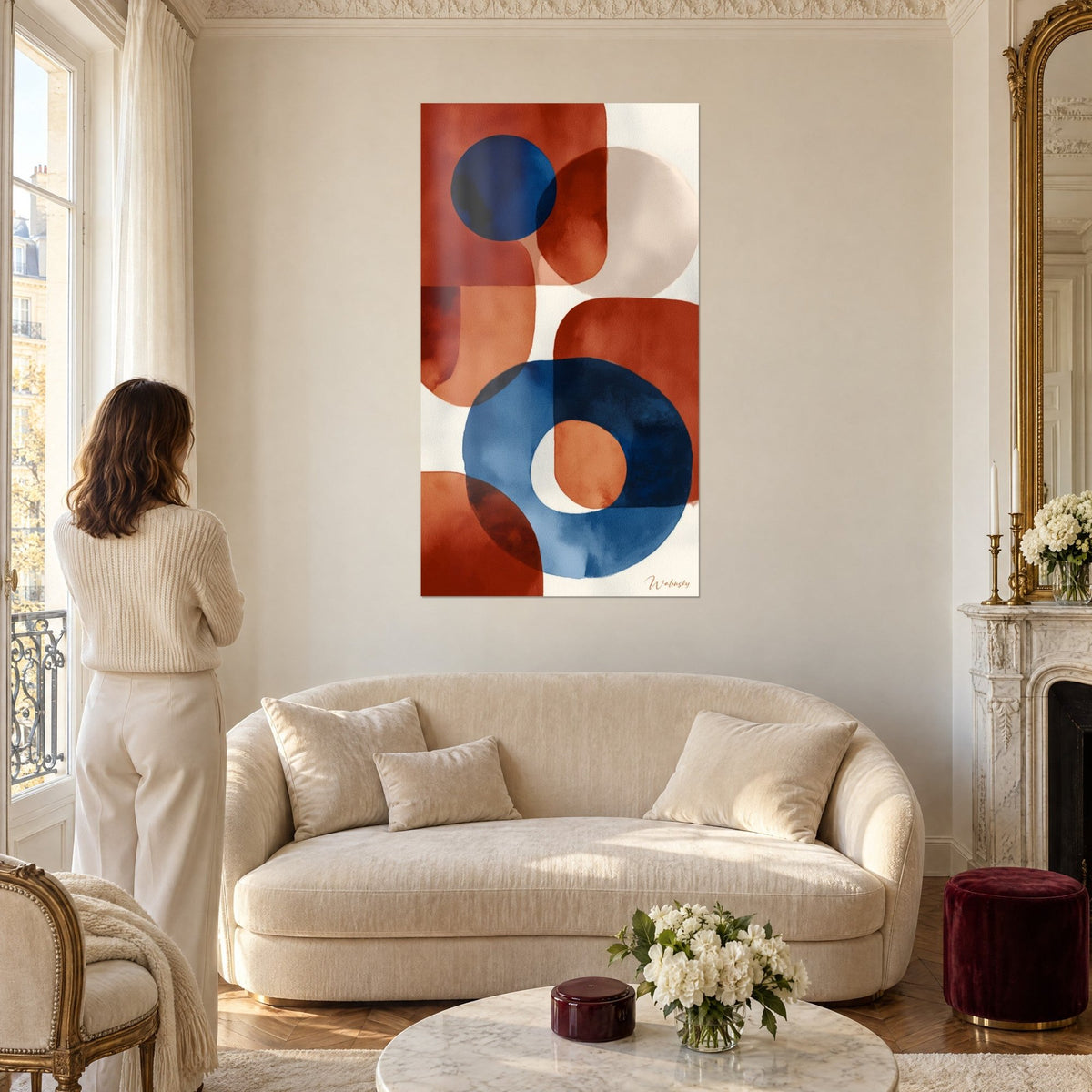 Gemälde mit runden Formen in Marineblau und Terrakotta auf cremefarbenem Grund, eine Frau von hinten, über einem Sofa in einem hellen Wohnzimmer