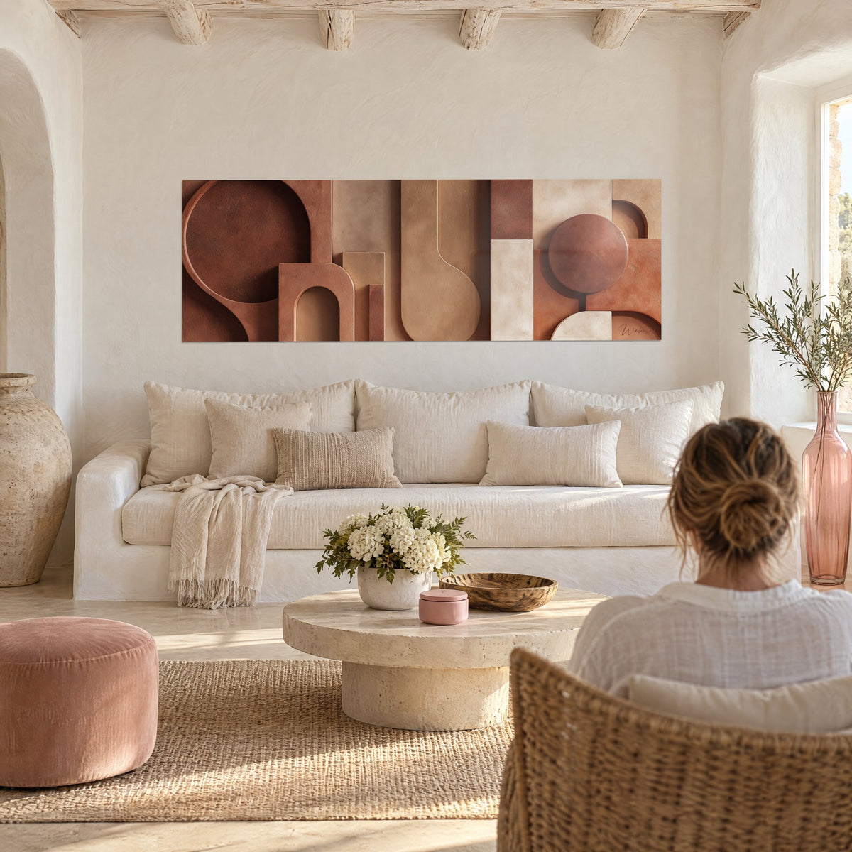 Wall art panoramic sculpted forms in brick and sand tones, dark ochre disc, above a sofa in a bright living room