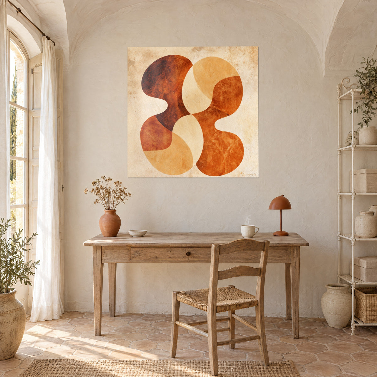 Quadro con lobi intrecciati ocra e ruggine su carta antica macchiata, appeso sopra una scrivania in legno chiaro e una sedia in paglia