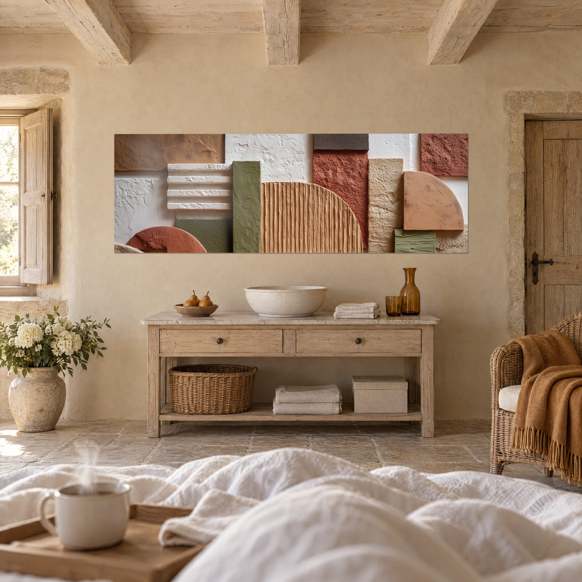 Tableau composition murale en aplats granuleux terracotta, olive et crème, au-dessus d'un lit dans une chambre claire