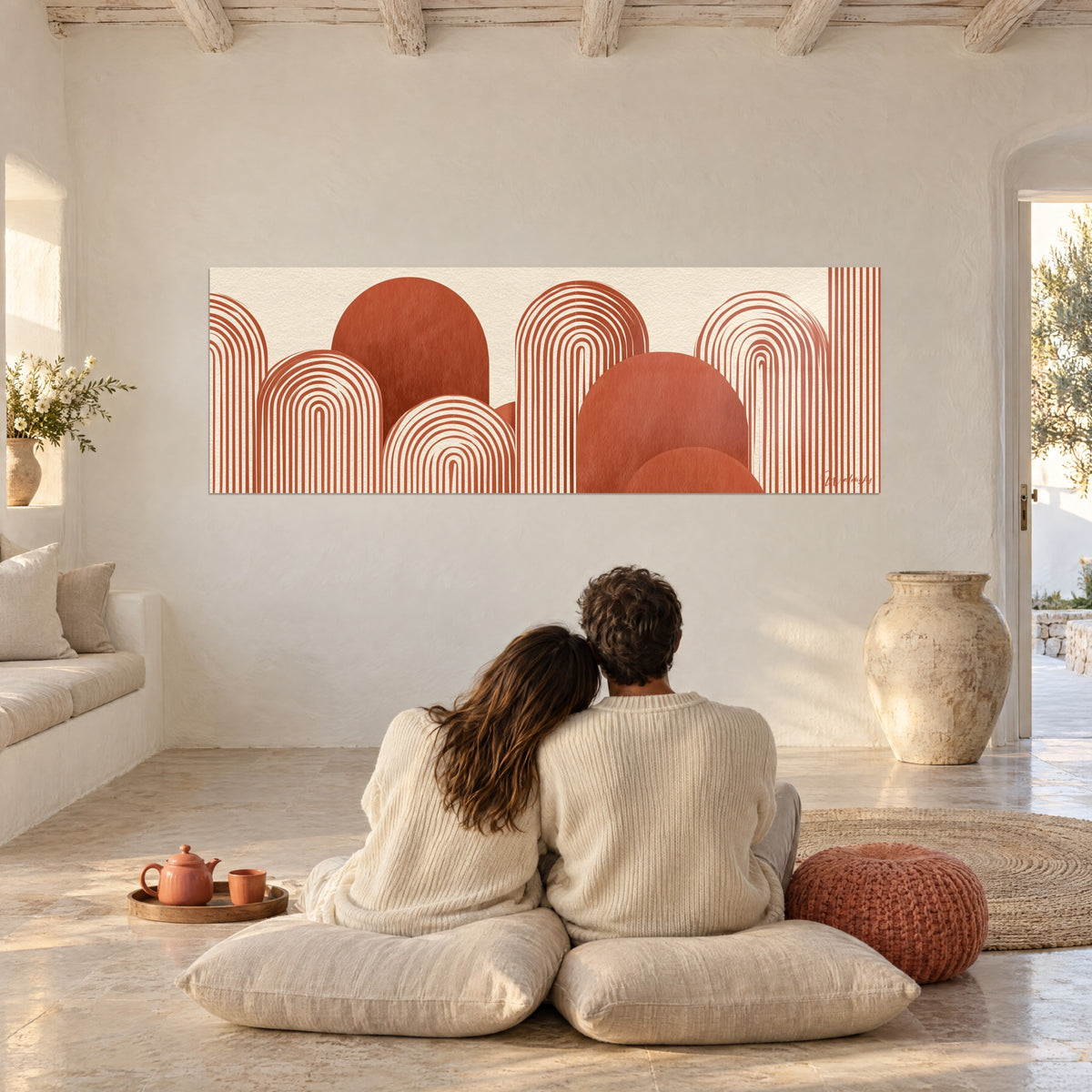 Tableau motif de collines en arcs terracotta sur fond crème, pièce voûtée blanche avec coussins beiges au sol