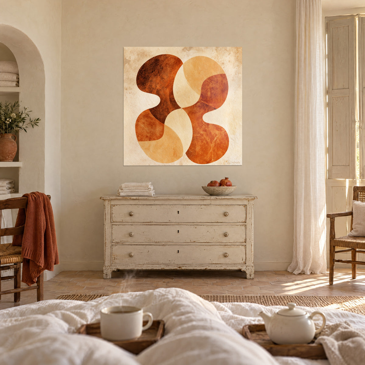 Quadro con arabeschi terracotta e crema su fondo invecchiato, appeso di fronte a una cassettiera patinata, sopra un letto in una camera luminosa