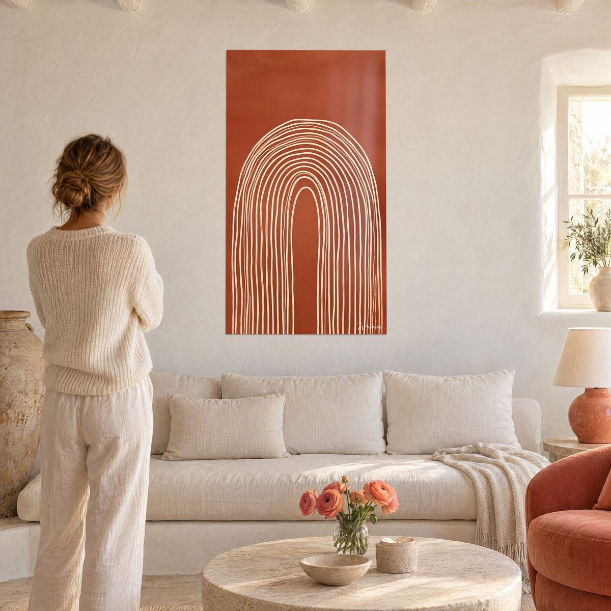 Wall art arch with concentric cream lines on brick background, woman seen from behind, above a sofa in a bright living room