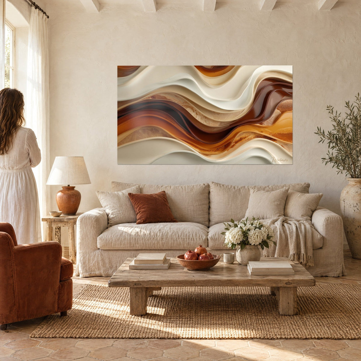Schilderij met ivoorkleurige en chocoladebruine golven met koperen reflecties, vrouw van achteren boven een bank in een lichte woonkamer