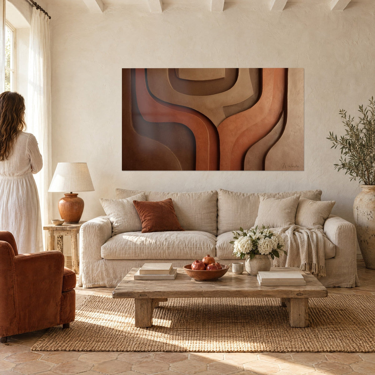 Wall art with wavy chocolate brown and terracotta bands in relief, seen from behind by a woman, above a sofa in a bright living room
