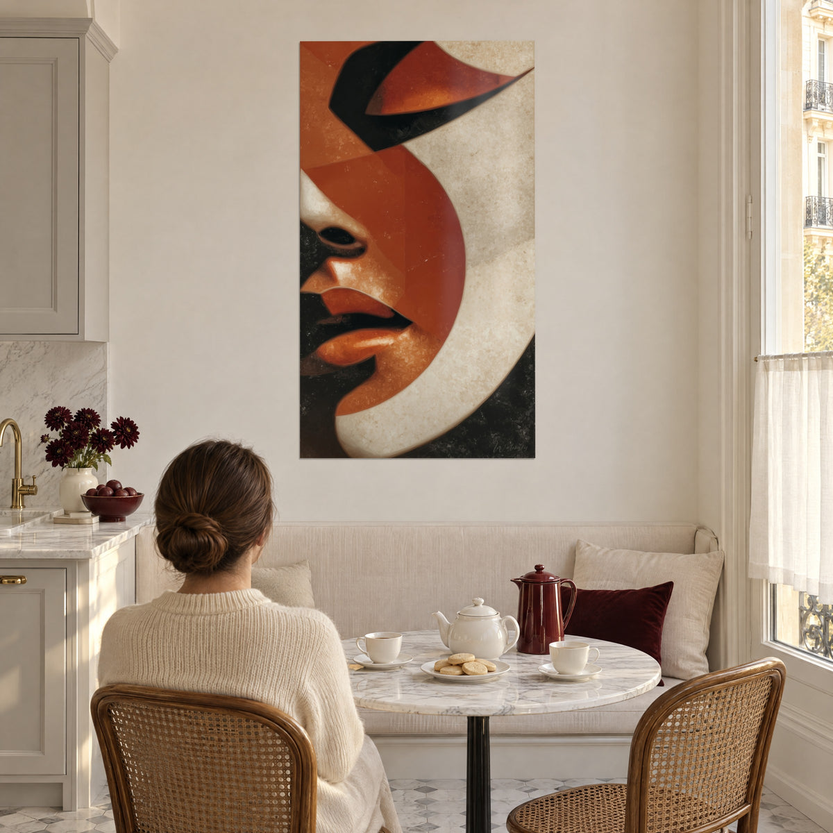 Quadro figura geometrica con palpebre nere e guancia ruggine, fascia crema, giovane donna di schiena a un tavolo da cucina
