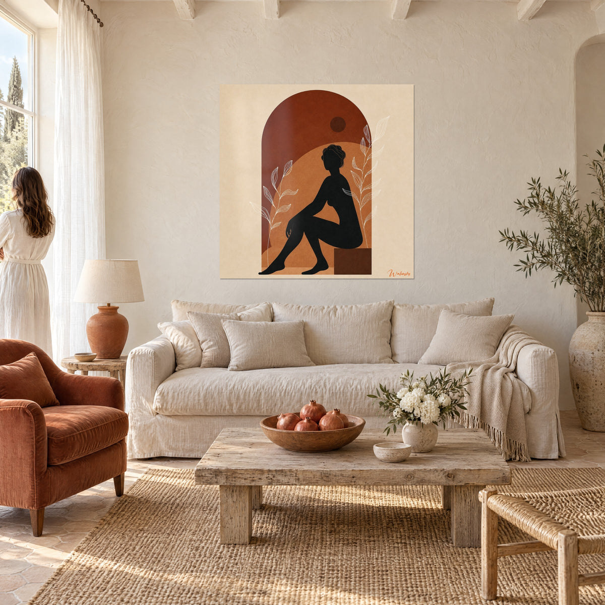 Tableau silhouette noire assise, genou plié sous une arche rouille et ocre, feuillage blanc, au-dessus d'un canapé dans un salon lumineux