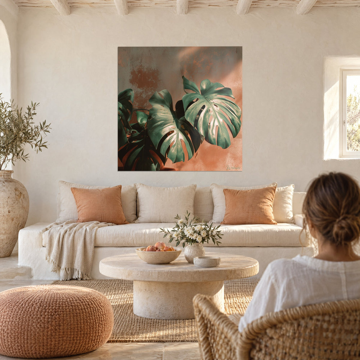 Wall art of sage green monstera leaves on a terracotta wall, raking light, above a sofa in a bright living room