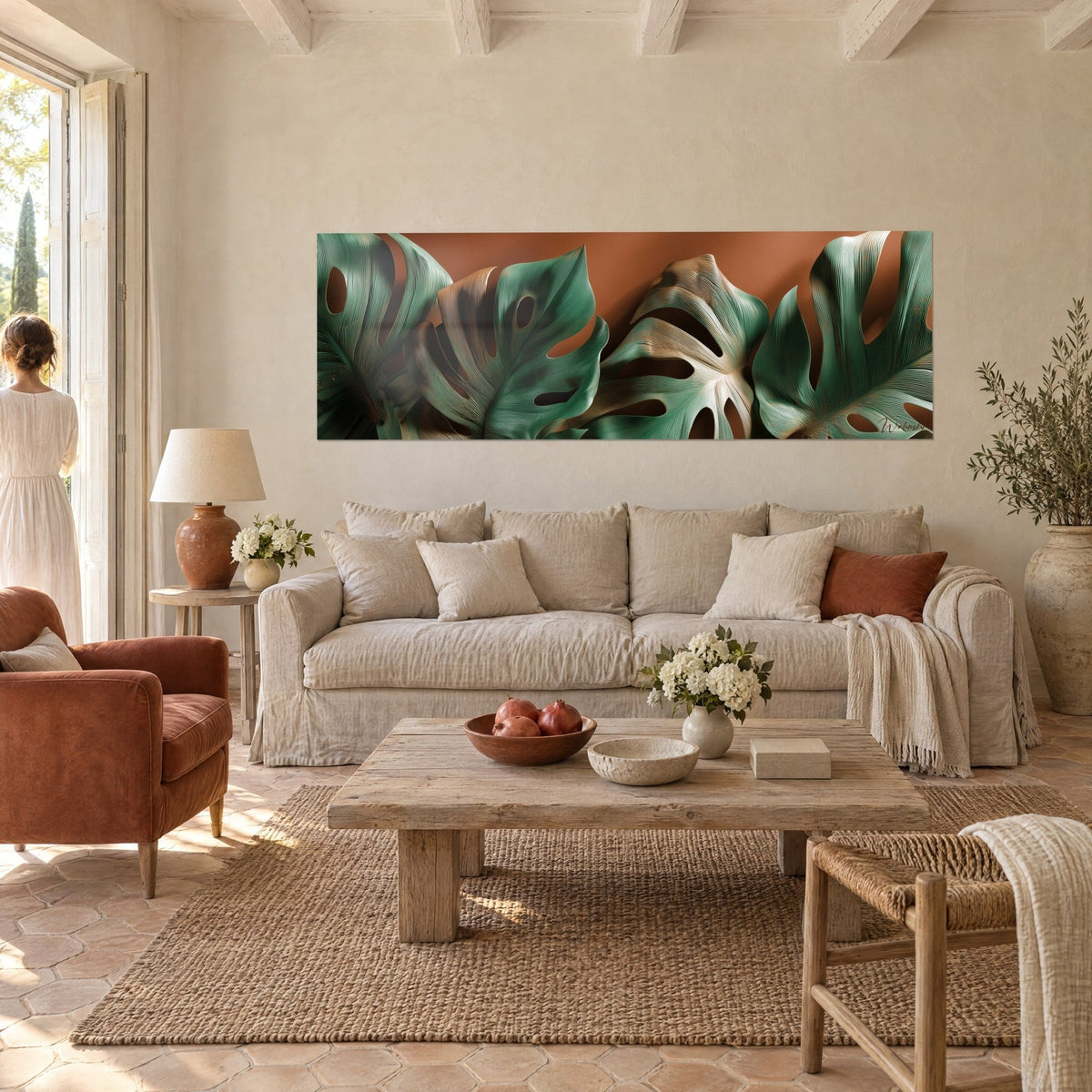 Cuadro con hojas de monstera caladas en verde salvia y cobre, fondo terracota, encima de un sofá en un salón luminoso