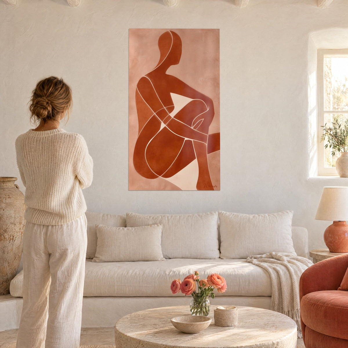 Schilderij van een zittende silhouet in baksteenrood met crème lijnen, knie stevig in de armen, vrouw van achteren boven een bank in een lichte woonkamer