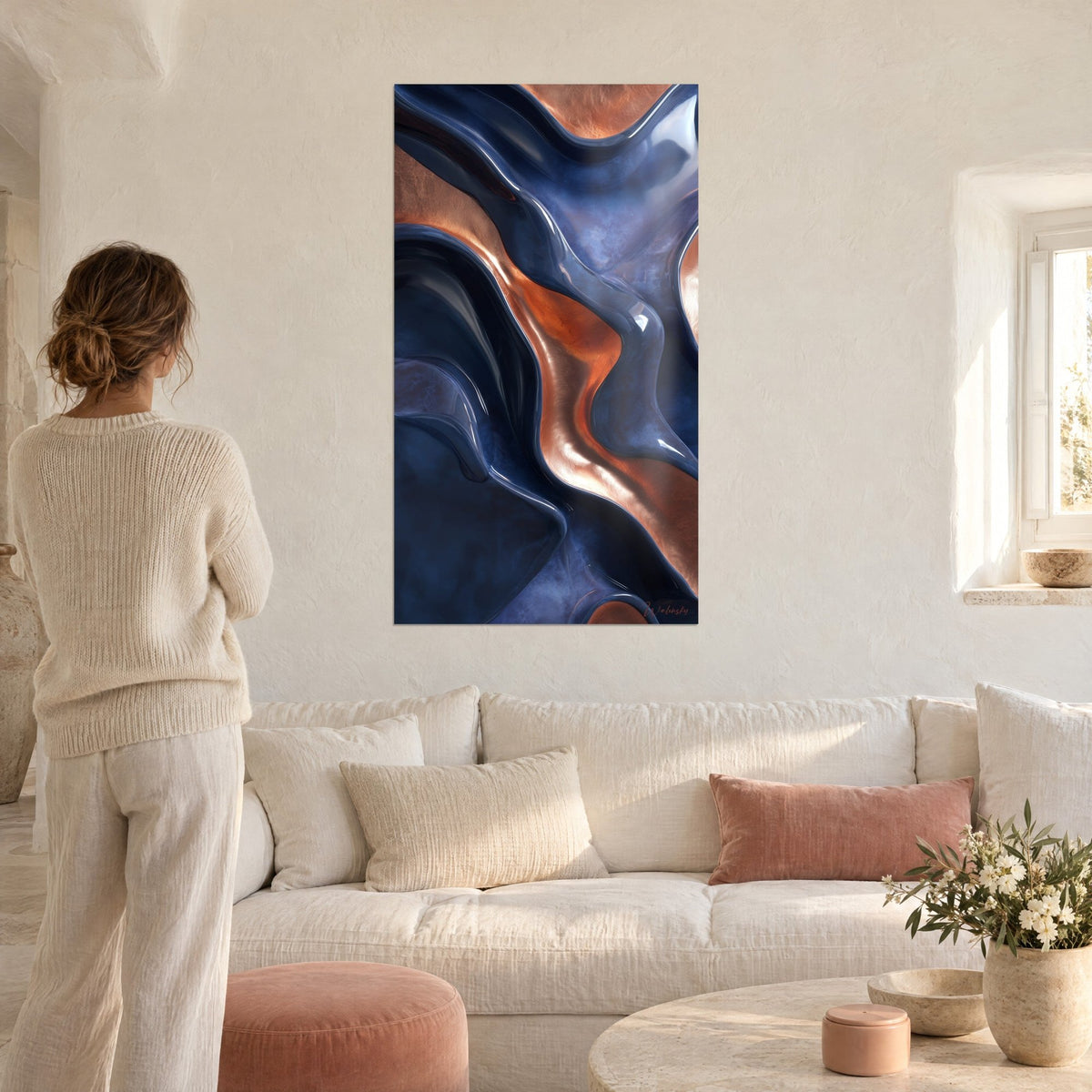 Cuadro olas esculpidas en azul marino y cobre, reflejos líquidos, mujer de espaldas con jersey crema, encima de un sofá en un salón luminoso