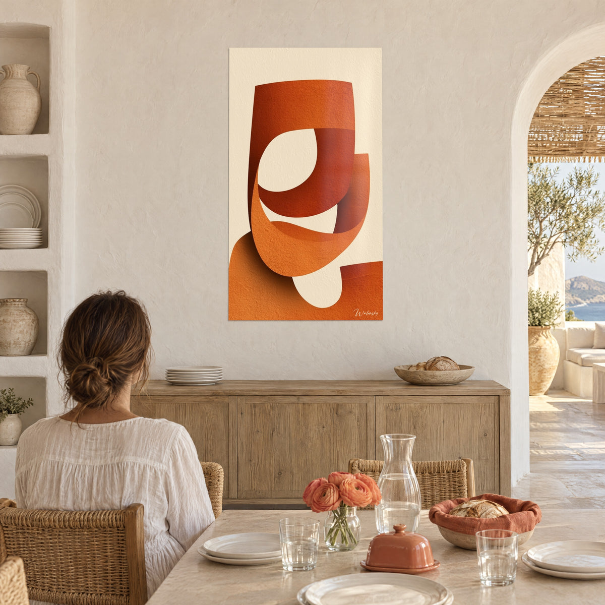 Schilderij oranje en roestkleurige lussen van gevouwen papier, crème achtergrond, vrouw van achteren aan tafel, in een Mediterraans huis