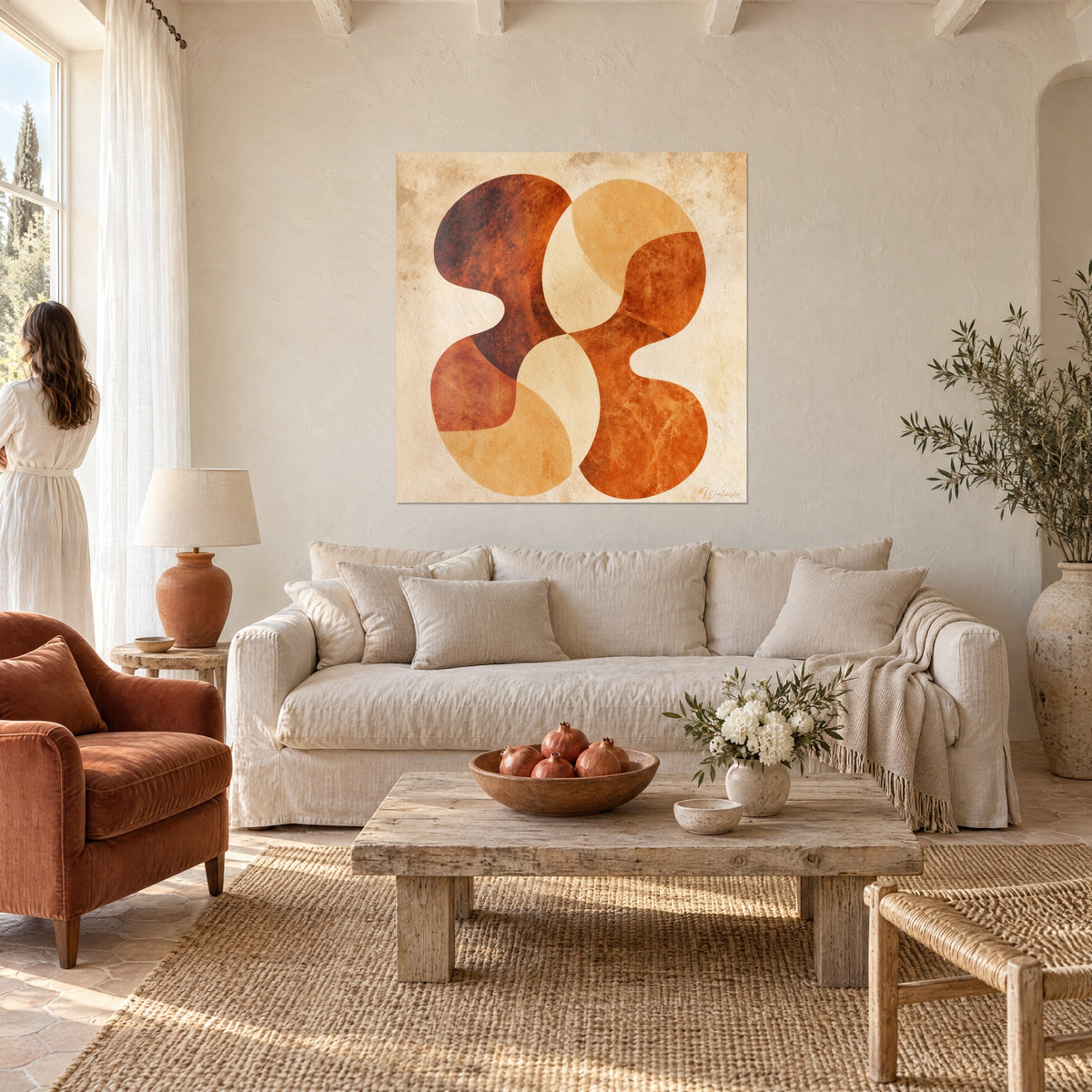 Wall art with wavy rust and beige shapes on aged paper, woman seen from behind in a white dress, above a sofa in a bright living room