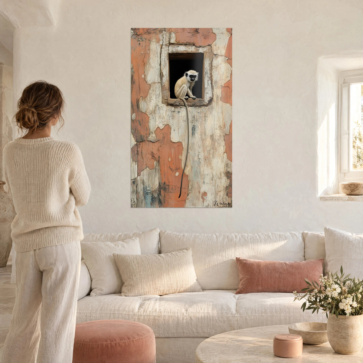 Cuadro joven mono de pelaje crema posado en una ventana negra, pared terracota desconchada, encima de un sofá en un salón luminoso