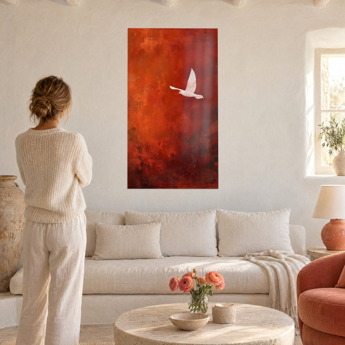 Wall art white dove in flight on a terracotta red background, wings spread, woman seen from behind above a sofa in a bright living room