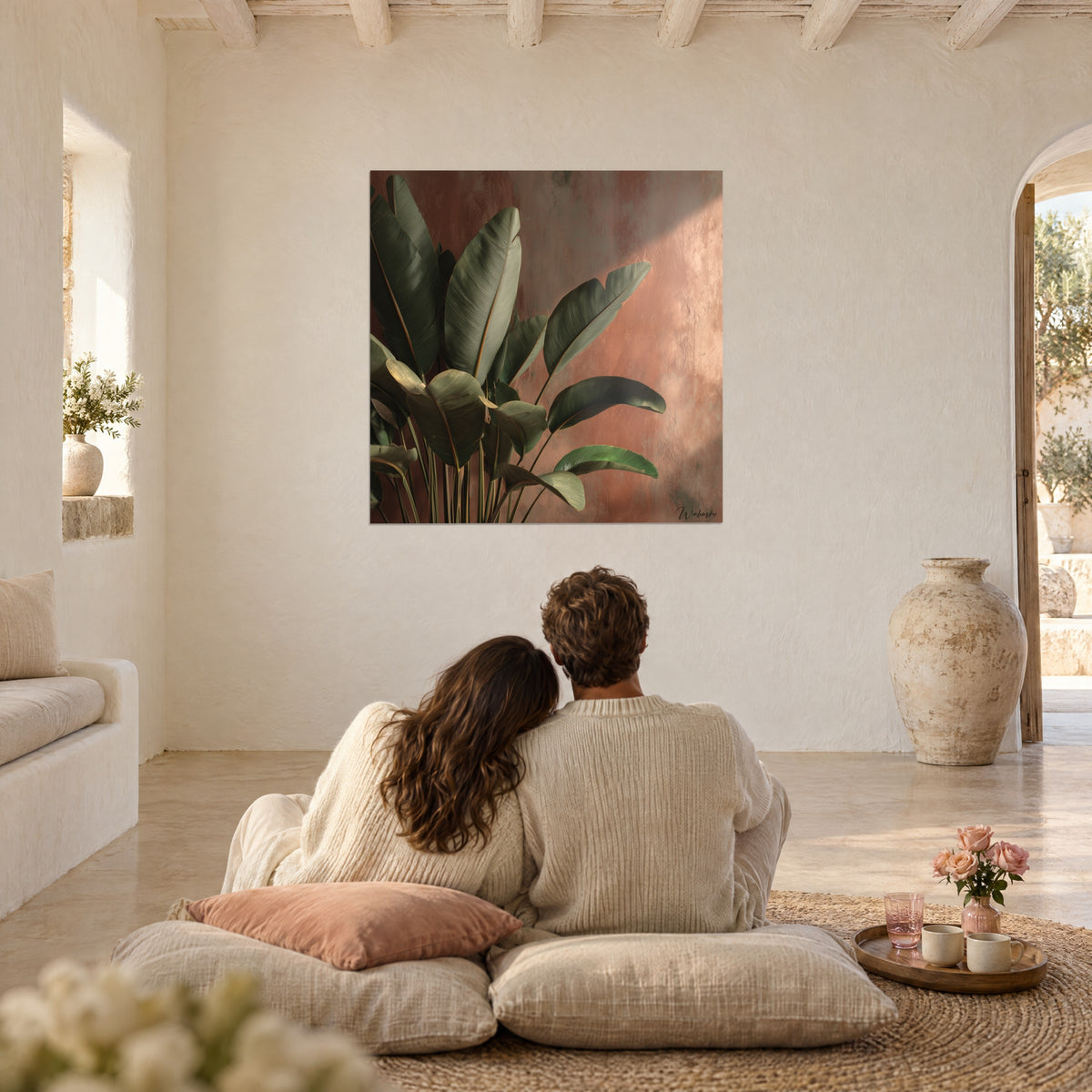 Tableau jungle de feuilles vert profond contre un crépi rose terre, couple enlacé de dos sur des coussins dans un salon voûté
