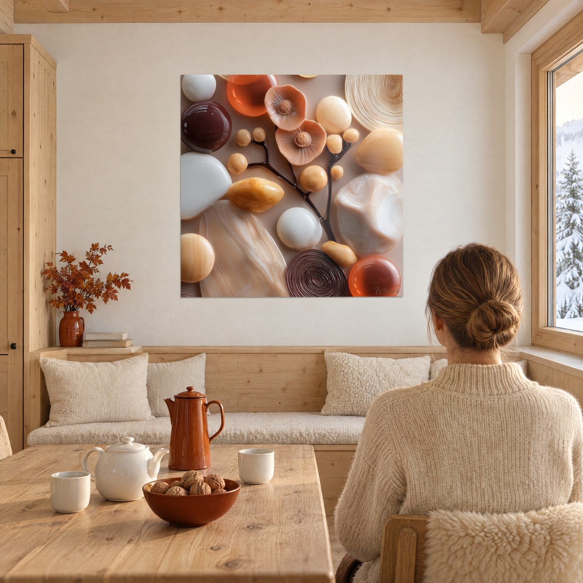 Tableau bouquet de pierres polies crème et ambre, spirale marron en relief, face à une table en bois dans un chalet enneigé
