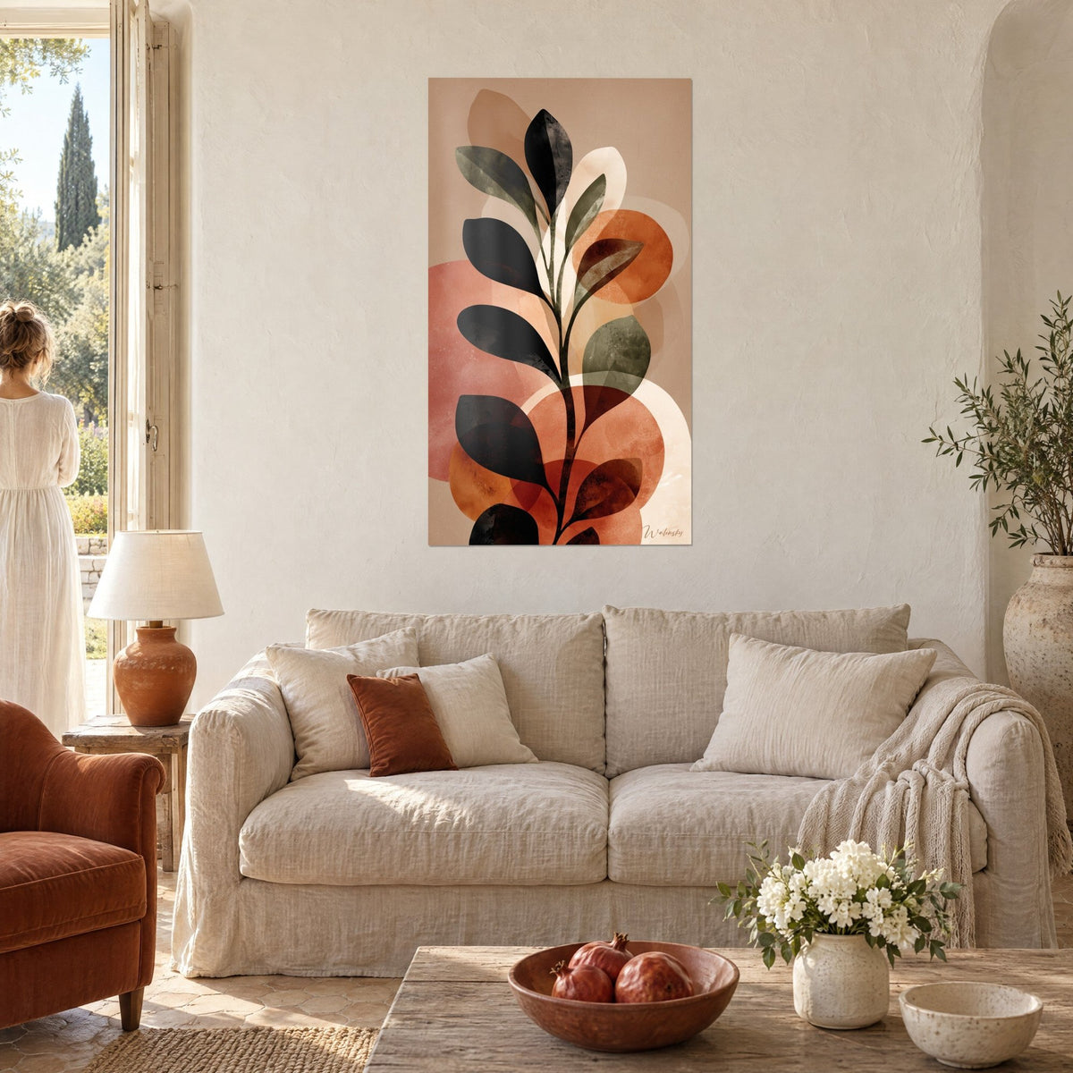 Tableau tige feuillue aux grandes feuilles noires et vert olive sur disques rose et orange, au-dessus d'un canapé dans un salon lumineux