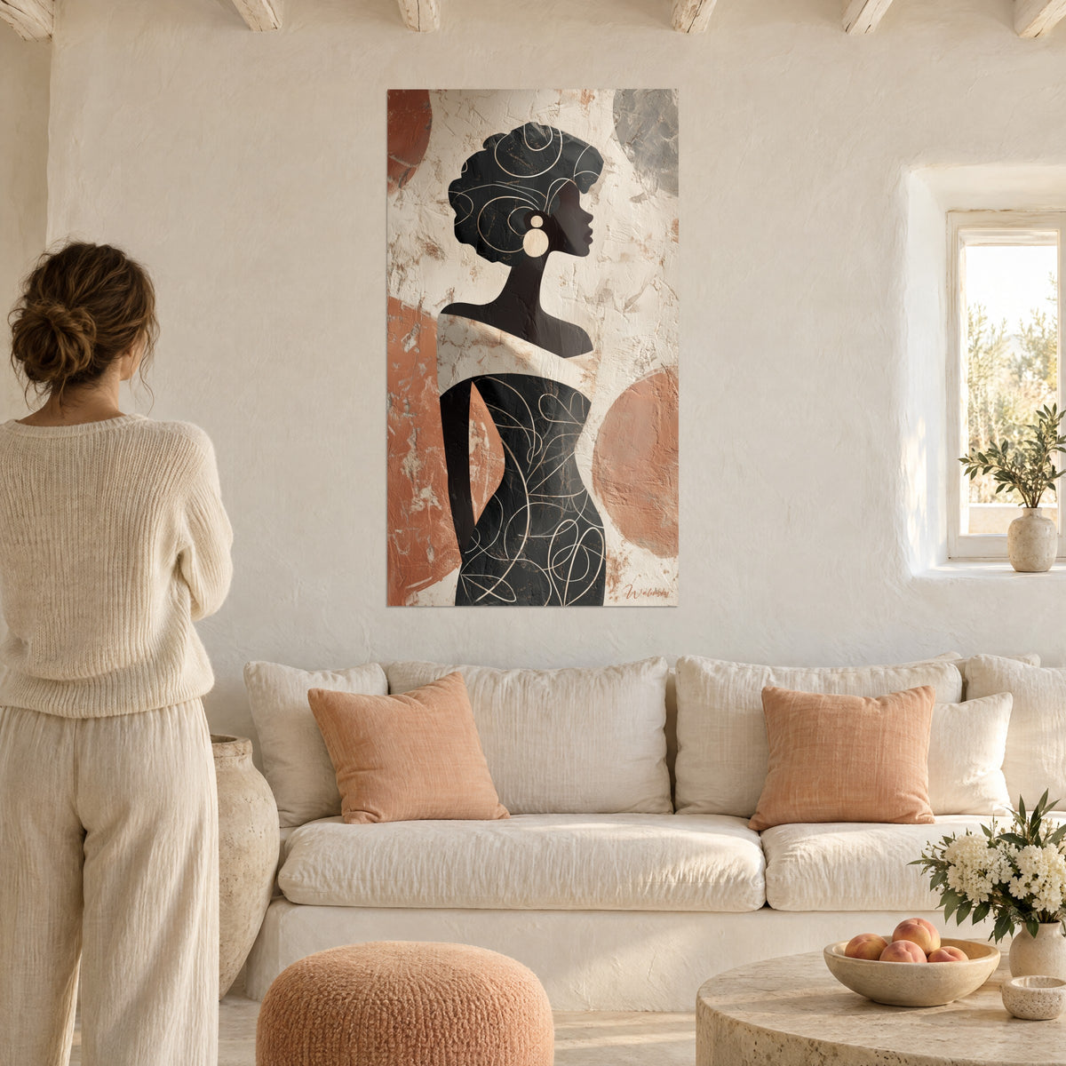 Tableau silhouette féminine noire au turban gravé de volutes ivoire, cercles terracotta, au-dessus d'un canapé dans un salon lumineux