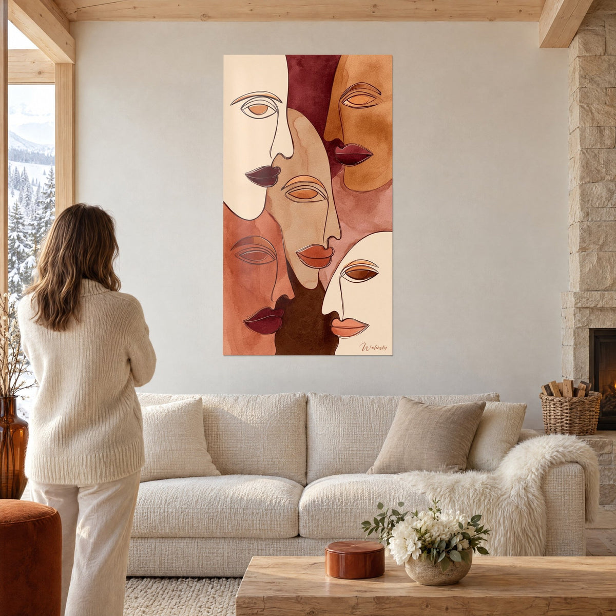 Tableau cinq visages stylisés ocre et bordeaux aux lèvres sombres, femme de dos, au-dessus d'un canapé dans un salon lumineux