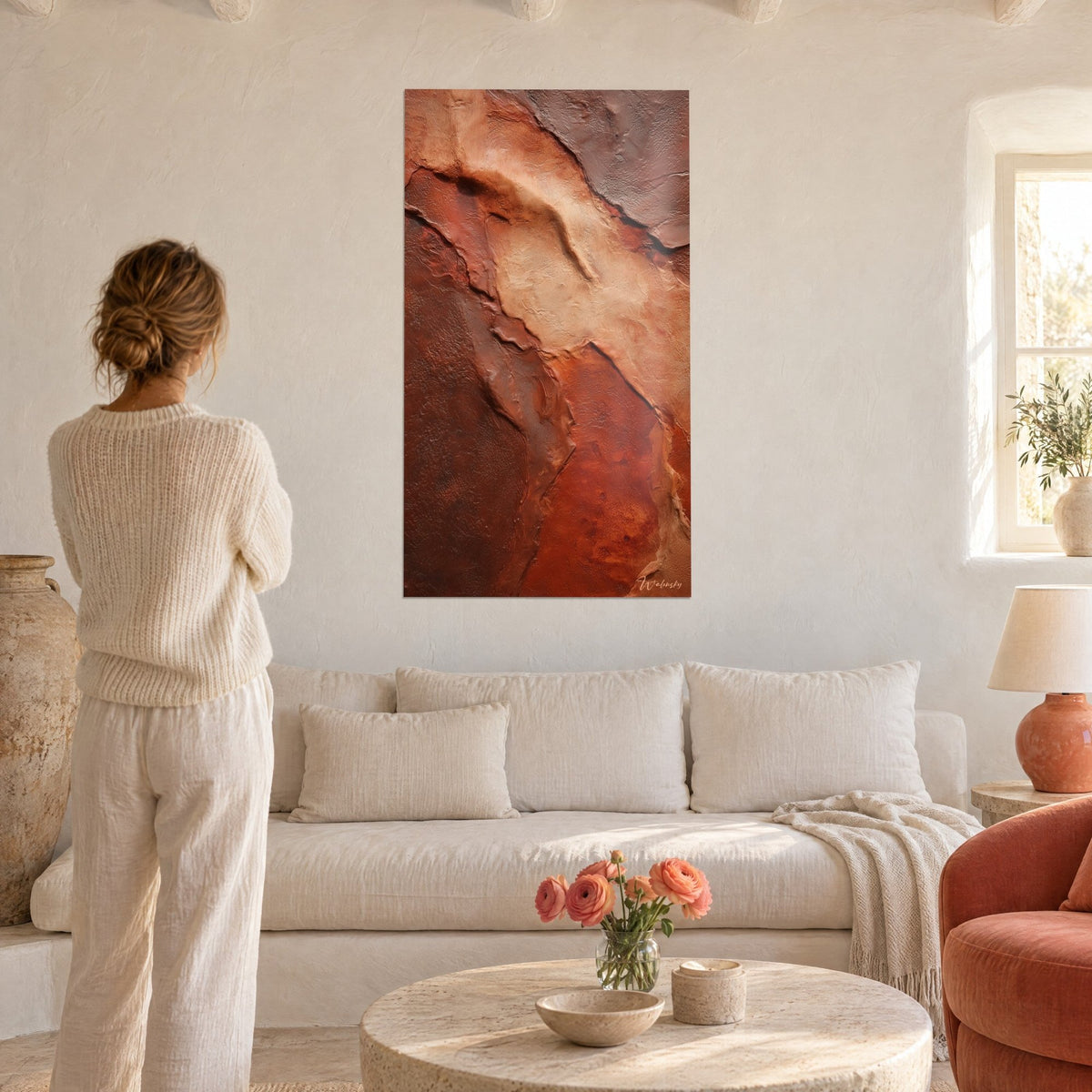 Quadro falesia rocciosa in ocra e marrone, strati screpolati di sabbia e ruggine, una donna di spalle sopra un divano in un soggiorno luminoso