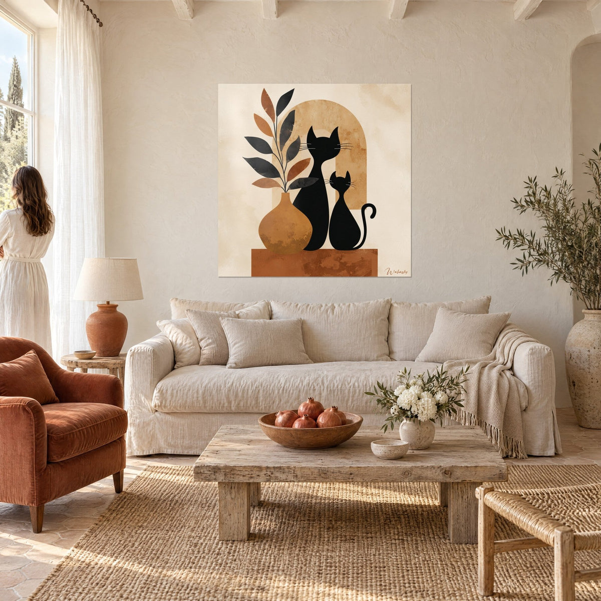 Tableau deux chats noirs sous une arche ocre, feuillage brun et noir, femme de dos, au-dessus d'un canapé dans un salon lumineux