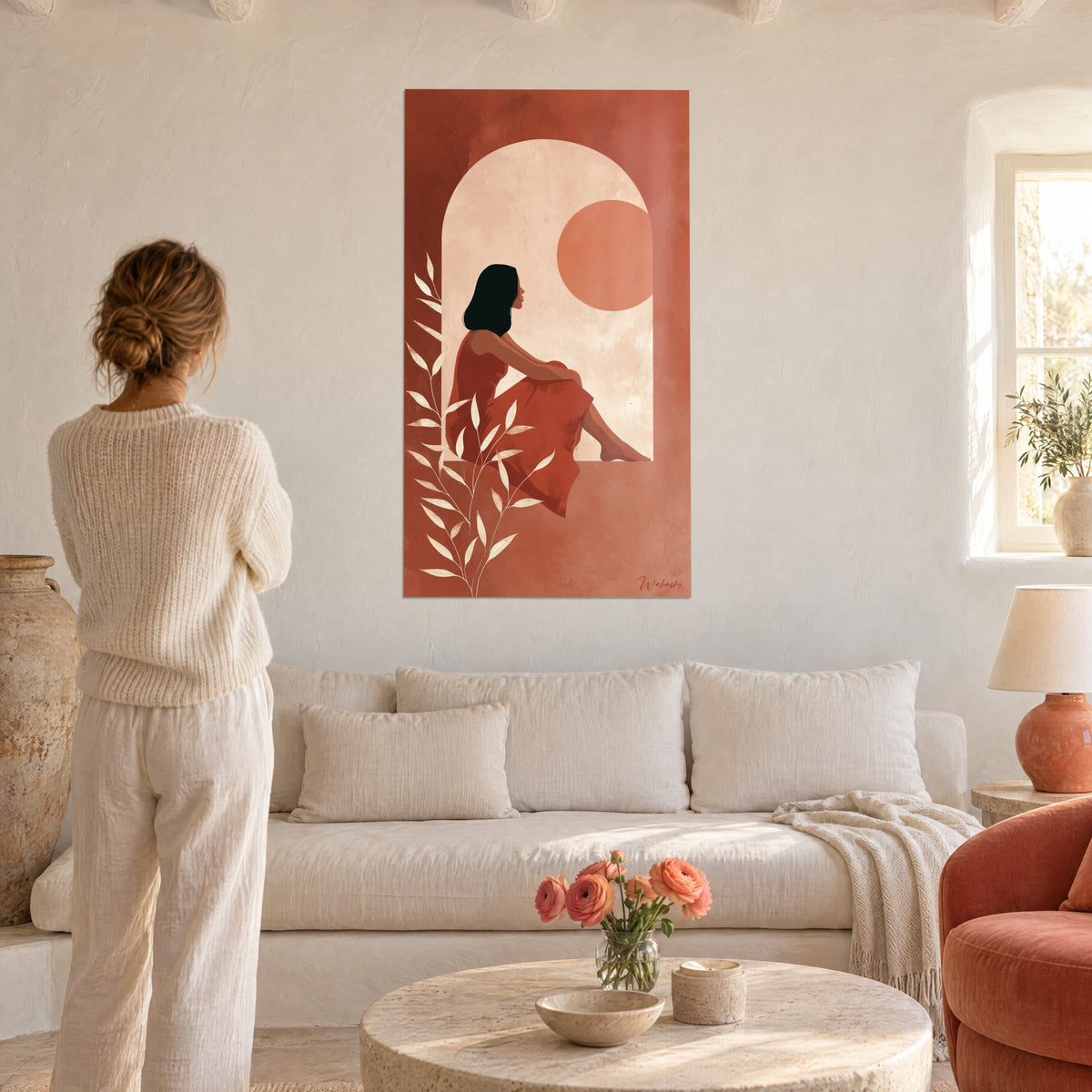Schilderij vrouw met zwart haar zittend op een vensterbank, terracottakleurige jurk en crèmekleurige boog, boven een bank in een lichte woonkamer