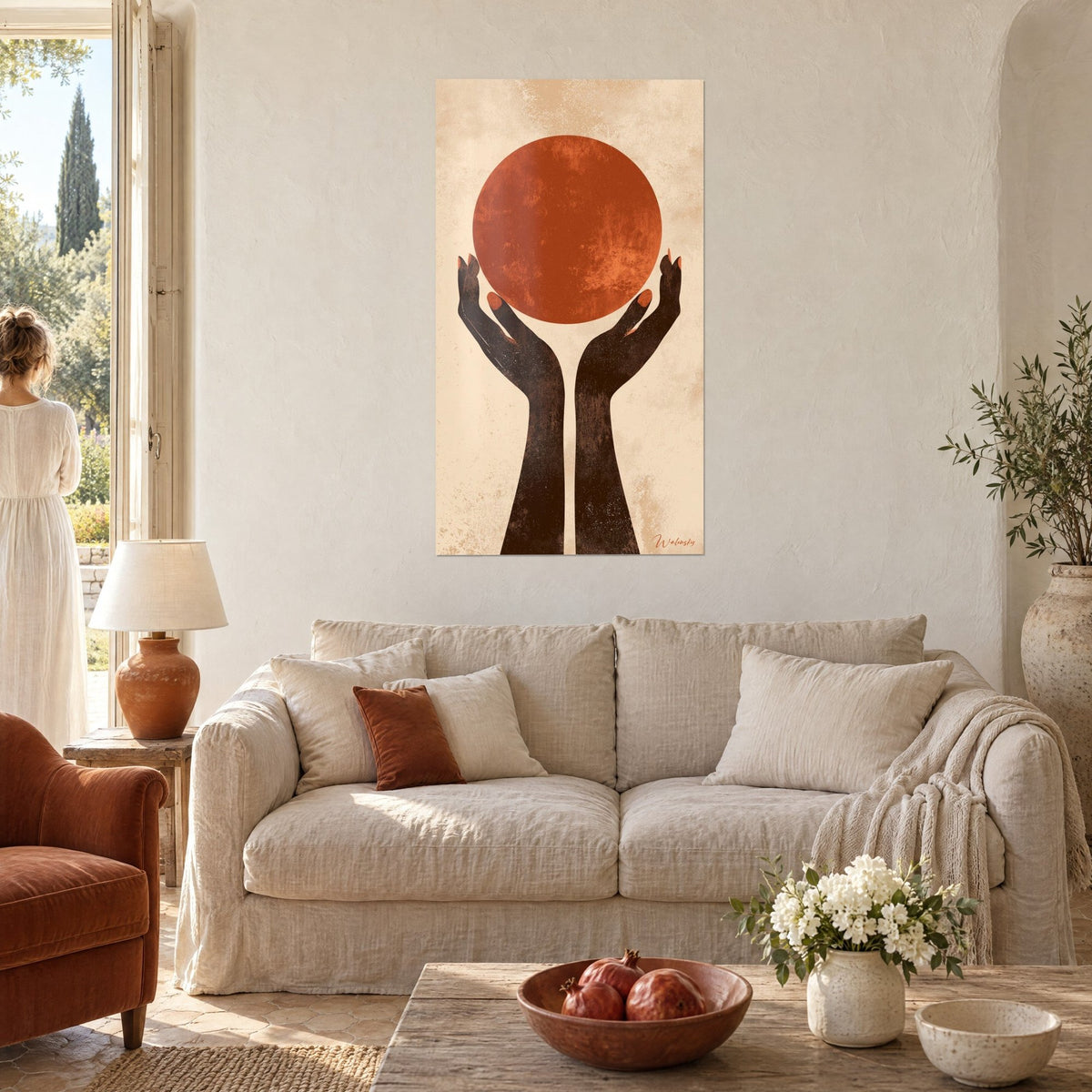 Wall art two brown hands lifting a rust-colored disc against a sand background, linen sofa and terracotta cushions, above a sofa in a bright living room