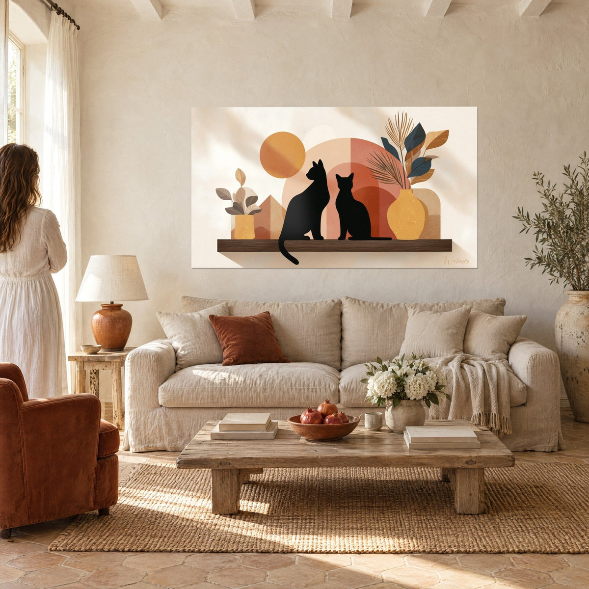 Quadro due gatti neri seduti su una mensola marrone, arco terracotta e sole ocra, donna di spalle, sopra un divano in un soggiorno luminoso