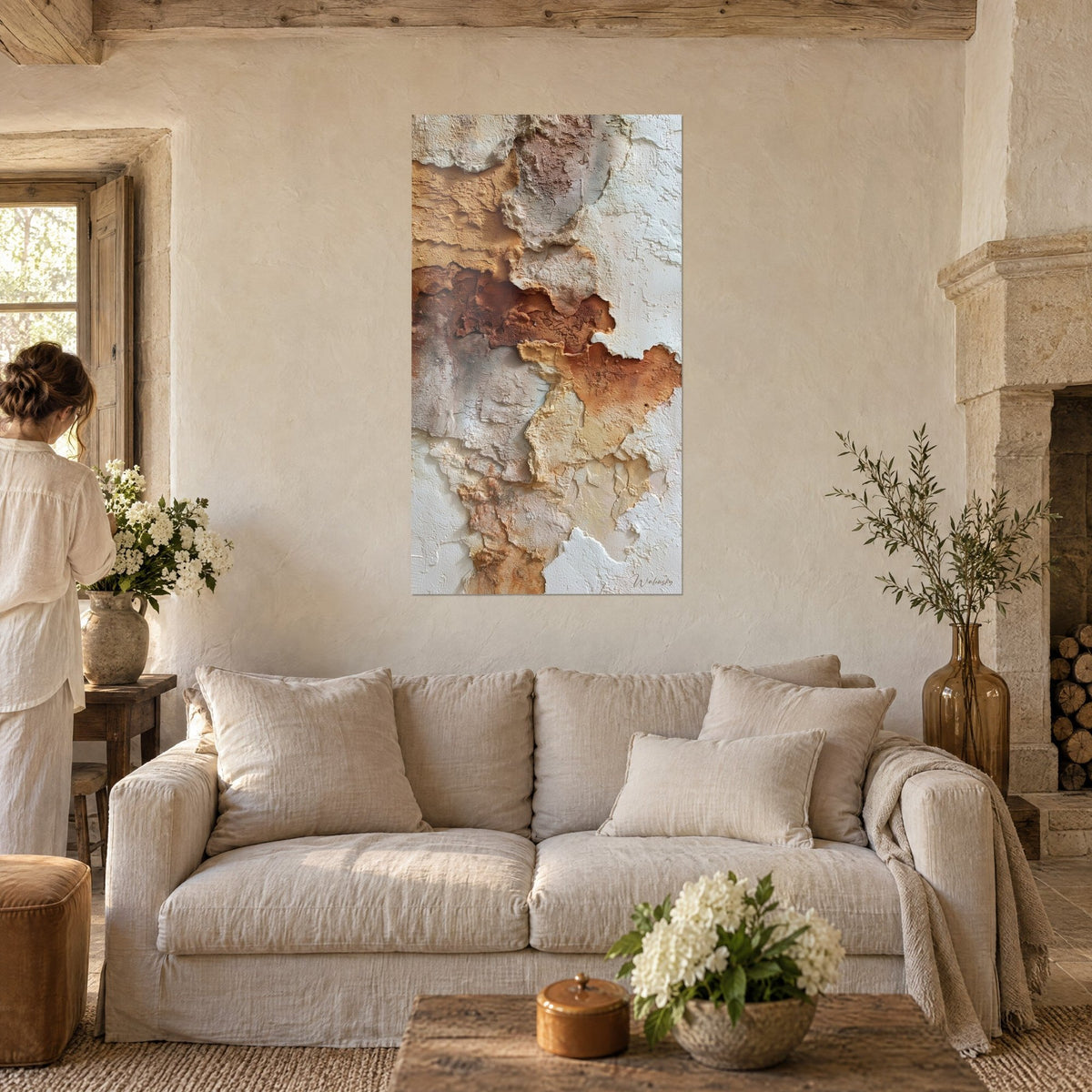 Tableau enduit craquelé aux croûtes blanches et rouille, silhouette de dos, au-dessus d'un canapé dans un salon lumineux