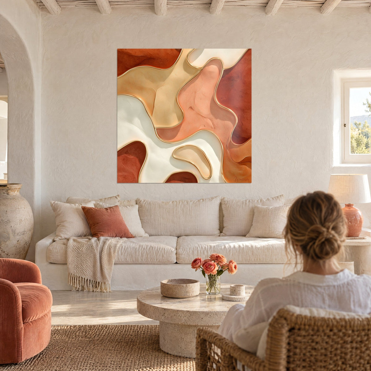 Wall art with sinuous ivory and terracotta shapes outlined in a fine gold edge, above a sofa in a bright living room