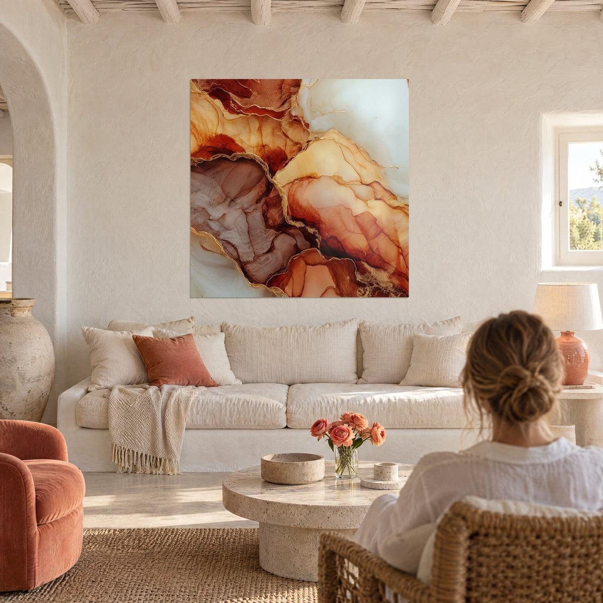Wall art with rust and cream marbling veined with gold lines, seen from behind a woman above a sofa in a bright living room
