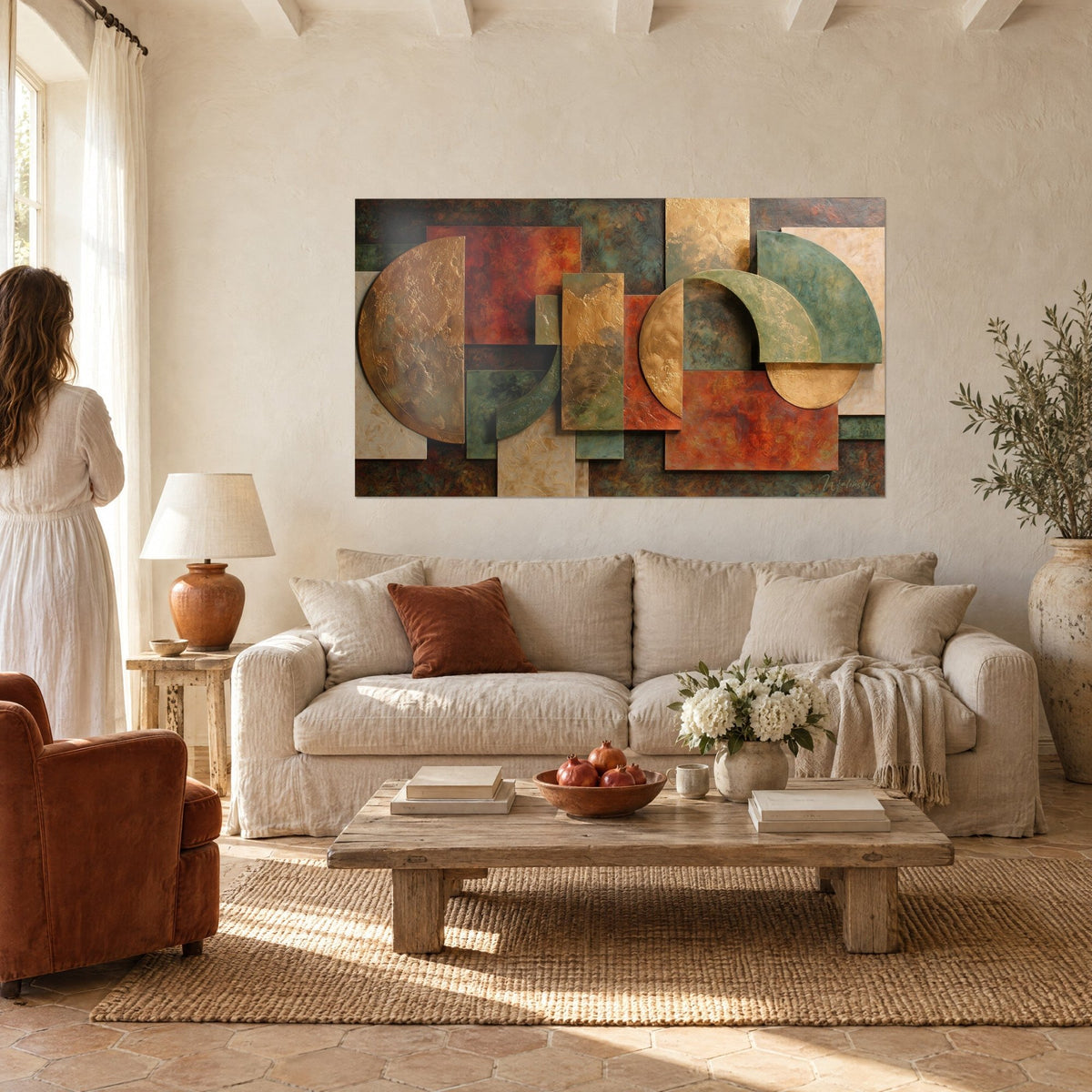 Wall art with gold half-discs and stacked terracotta blocks, green patina, woman seen from behind, above a sofa in a bright living room