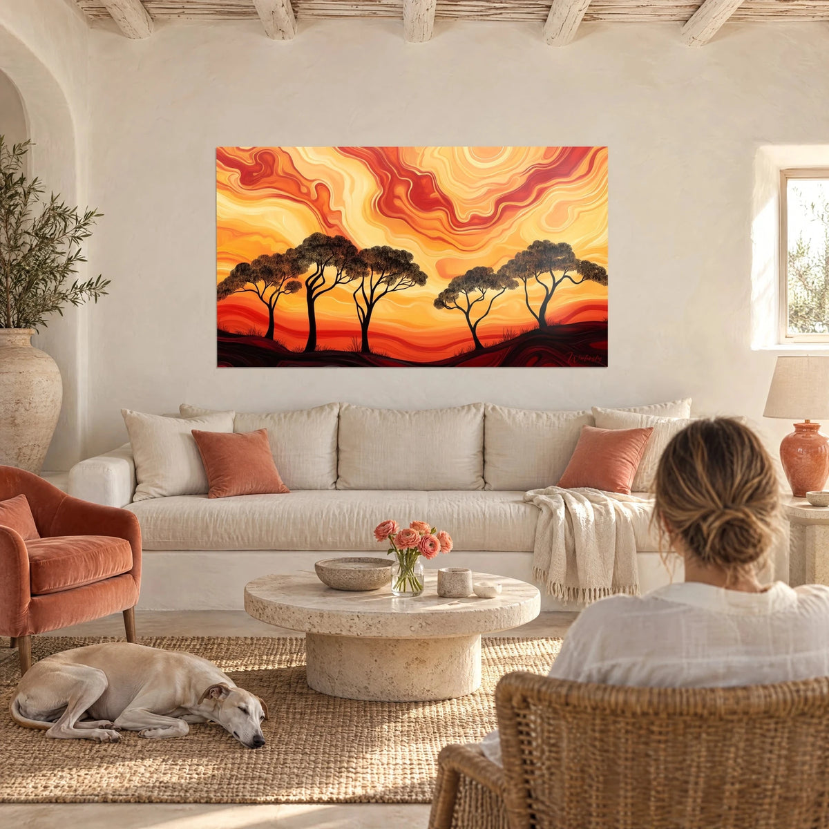Gemälde mit schwarzen Schirmakazien unter einem wirbelnden orangeroten und gelben Himmel, über einem Sofa in einem hellen Wohnzimmer