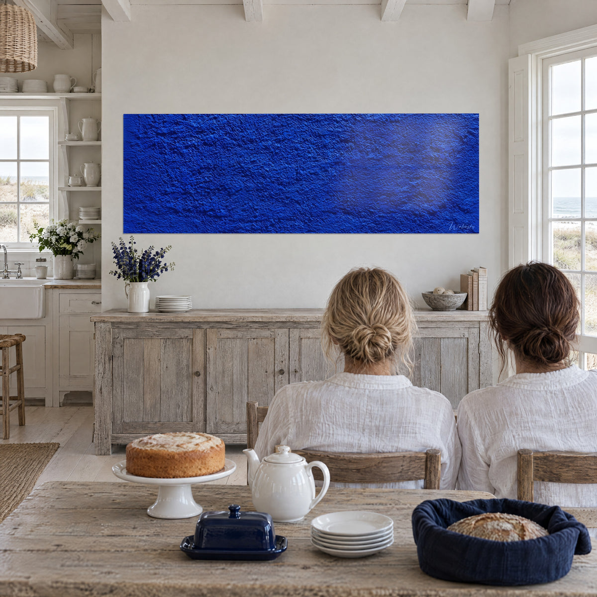 Cuadro paisaje mineral azul zafiro de asperezas finas, sombras índigo, frente a dos mujeres de espaldas junto a una ventana