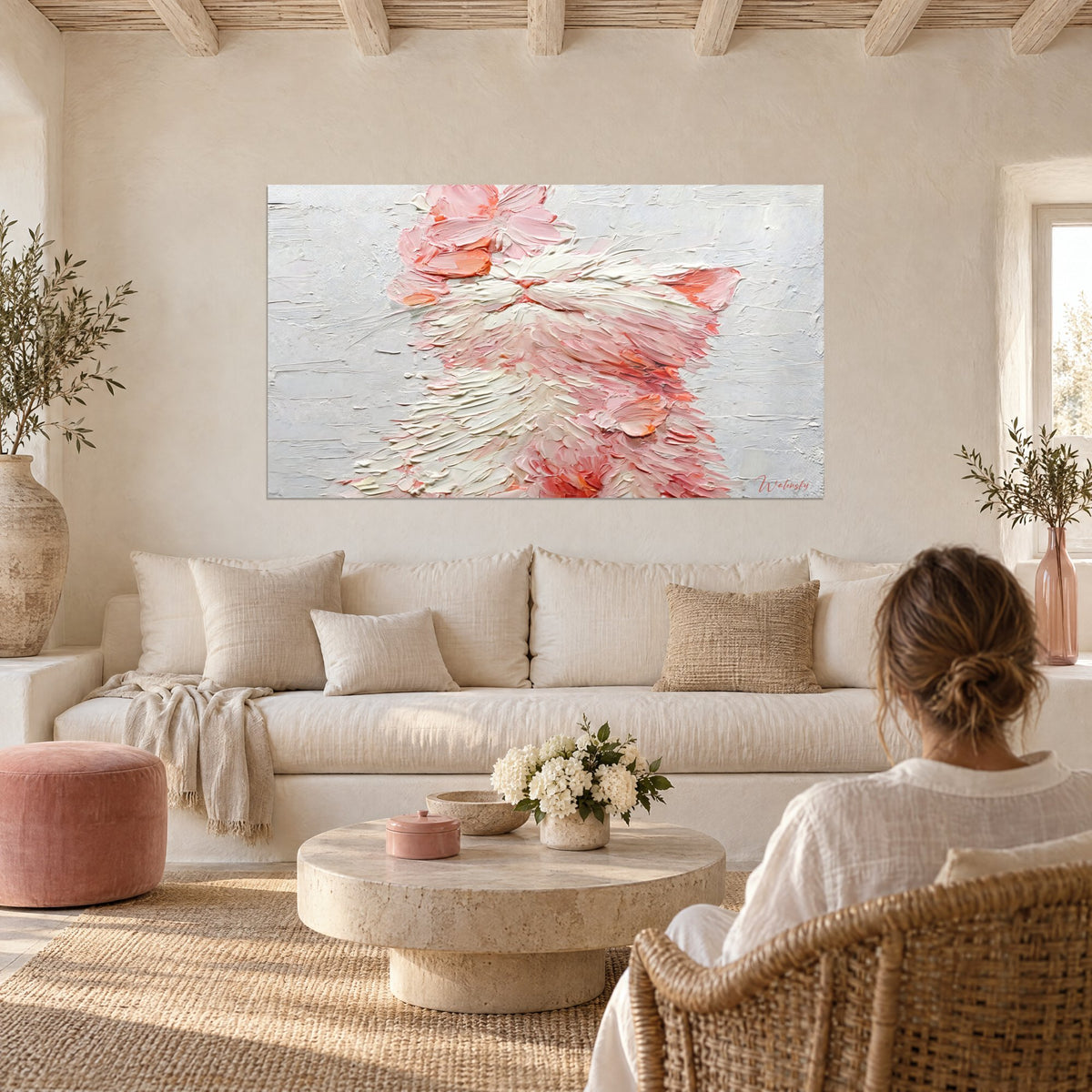 Tableau chaton blanc aux pétales roses en empâtements crème et corail, au-dessus d'un canapé dans un salon lumineux